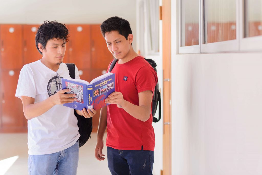 Foto de dos estudiantes leyendo un libro.