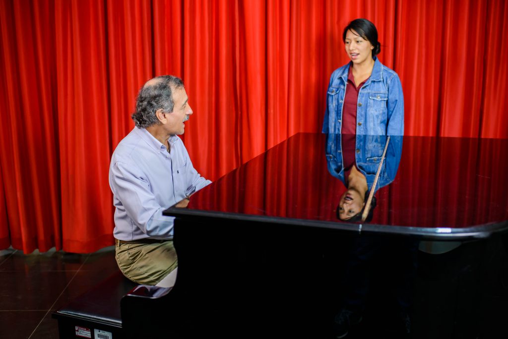 Foto de docente practicando canto con estudiante.