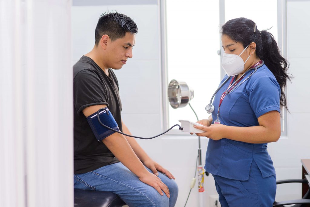 Foto (en plano americano) de personal de salud de la Dirección de Bienestar Universitario brindando atención médica a estudiante.