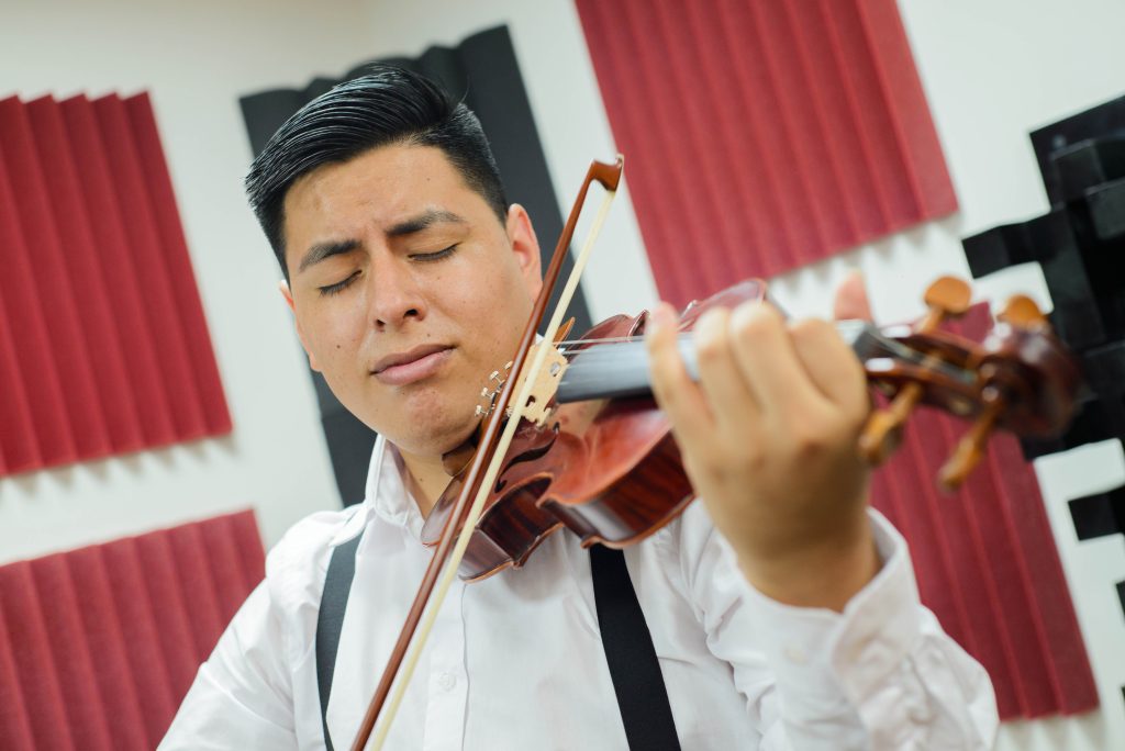 Foto de estudiante ejecutando pieza musical con violín.